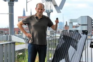 Sönke Tangermann, Vorstand von Green Planet Energy mit dem Stecker eines PV-Moduls "Simon" in der Hand.