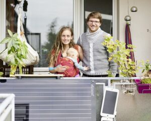 Patrick Held, seine Freundin Toni und die gemeinsame Tochter Parvaneh auf dem Balkon ihrer Wohnung. Im Vordergrund: das Mini-Solarkraftwerk simon.