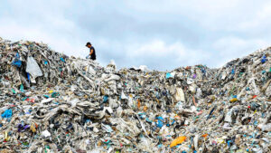 Ein Mensch der über Müllberge in Malaysia klettert.