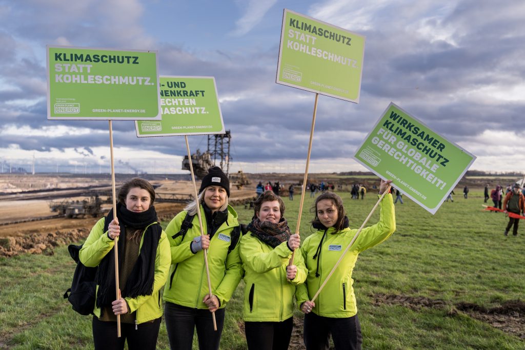 Vier Mitarbeiter:innen von Green Planet Energy die Plakate am Protest-Sonntag in Lützerath hochhalten.